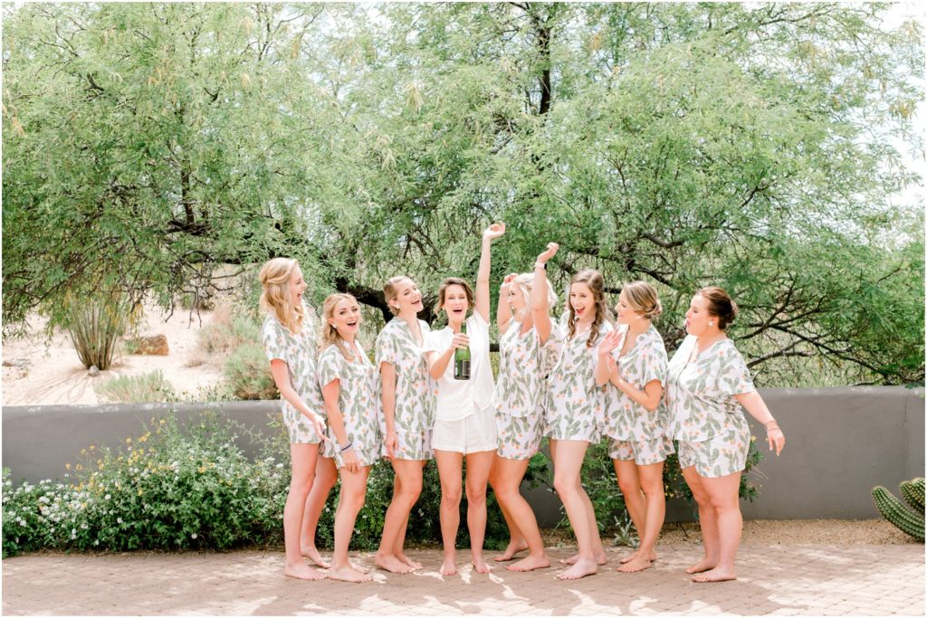 bride and bridesmaids in robes popping champagne